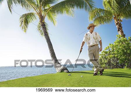 Hawaii, Oahu, Caucasion Male Standing And Posing With A Golf Club And Golf Ball In Hand At A Beautiful Tropical Beachfront Golf Course Turf View Large Photo Image Stock Photo - Hawaii, Oahu, Caucasion Male Standing And Posing With A Golf Club And Golf Ball In Hand At A Beautiful Tropical Beachfront Golf Course Turf. Fotosearch