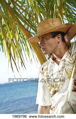Hawaii, Oahu, Closeup Headshot Of European Male Wearing Aloha Shirt With White Kukui Nut Lei And Rafia Hat, Palm Frond In The Background. View Large Photo Image Stock Photograph - Hawaii, Oahu, Closeup Headshot Of European Male Wearing Aloha Shirt With White Kukui Nut Lei And Rafia Hat, Palm Frond In The Background.. Fotosearch