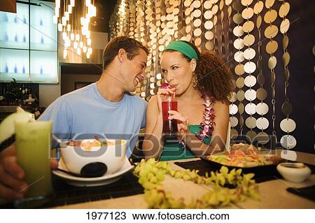 Stock Image - Hawaii, Oahu, Couple Feeding Each Other At A Trendy Restaurant.. Fotosearch