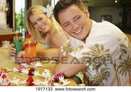 Stock Image - Hawaii, Oahu, Couple Having Drinks At A Bar.. Fotosearch