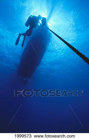 Stock Image - Hawaii, Oahu, Diver Silhouetted On Anchor Line, View Of Boat From Below. Fotosearch