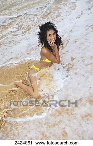 Stock Image - Hawaii, Oahu, Eternity Beach, Beautiful girl sitting in the tide.. Fotosearch