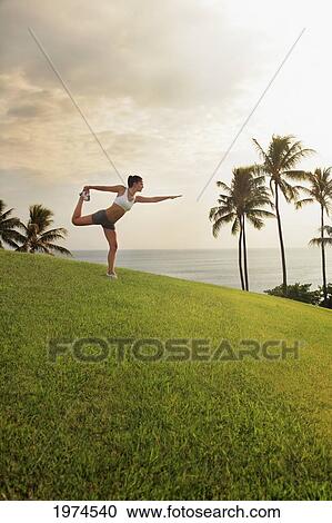 Hawaii, Oahu, Female Doing A Yoga Pose, Stretching On A Hill Overlooking Ocean, Palm Trees And Sunset. View Large Photo Image Stock Image - Hawaii, Oahu, Female Doing A Yoga Pose, Stretching On A Hill Overlooking Ocean, Palm Trees And Sunset.. Fotosearch