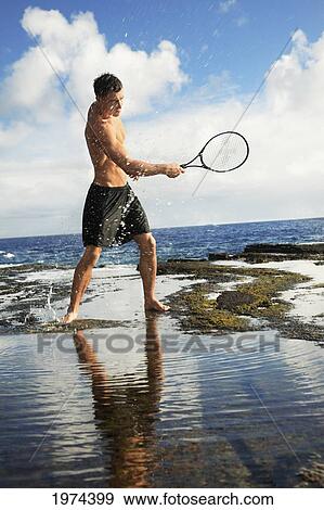 Hawaii, Oahu, Fit Male Swinging A Tennis Racket At The Tidepool. View Large Photo Image Stock Photo - Hawaii, Oahu, Fit Male Swinging A Tennis Racket At The Tidepool.. Fotosearch