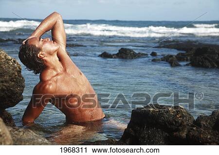 Stock Image - Hawaii, Oahu, Fit Young Male Enjoying A Warm Day In A Tidepool.. Fotosearch