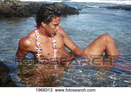 Stock Image - Hawaii, Oahu, Fit Young Male Wearing A Lei And Enjoying A Warm Day In A Tidepool.. Fotosearch