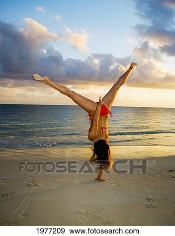 Stock Photo - Hawaii, Oahu, Girl On Beach In Swimsuit Doing Gymnastics.. Fotosearch
