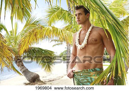 Picture - Hawaii, Oahu, Headshot Of A European Male Wearing A White Shell Necklace Standing In Front Of A Palm Frond At The Beach.. Fotosearch