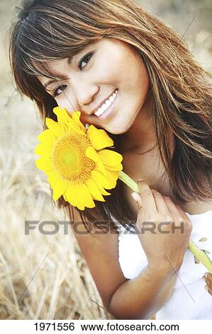 Stock Photograph - Hawaii, Oahu, Headshot Of Beautiful Asian Woman With Sunflower.. Fotosearch