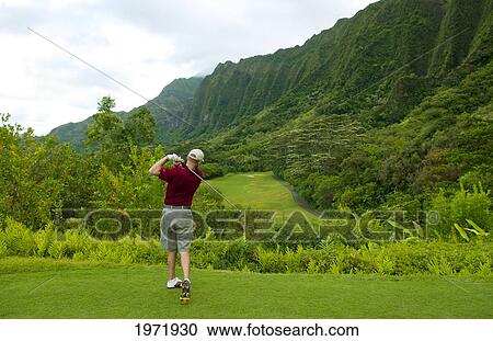 Stock Image - Hawaii, Oahu, Honolulu, Ko'olau Golf Course, Man Tees Off At The Fifteenth Hole.. Fotosearch