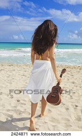Stock Image - Hawaii, Oahu, Kailua Beach, Beautiful walks torwards ocean with ukulele.. Fotosearch