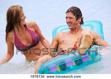 Picture - Hawaii, Oahu, Kailua Beach, Couple Plays In Water With An Inflatable Raft.. Fotosearch
