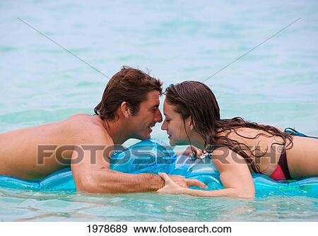 Stock Photo - Hawaii, Oahu, Kailua Beach, Couple Sharing Romantic Moments In Water On Inflatable Rafts.. Fotosearch