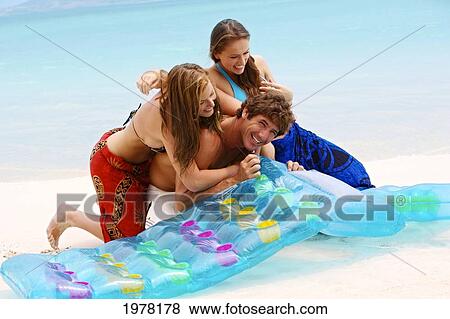 Stock Photo - Hawaii, Oahu, Kailua Beach, Young Man And Women Blow Up A Raft At The Waters Edge.. Fotosearch