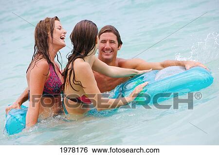 Hawaii, Oahu, Kailua Beach, Young Man And Women Playing In The Water On An Inflatable Raft. View Large Photo Image Stock Photograph - Hawaii, Oahu, Kailua Beach, Young Man And Women Playing In The Water On An Inflatable Raft.. Fotosearch