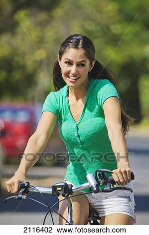 Stock Image - Hawaii, Oahu, Kailua, Beautiful young woman enjoying a bike ride on a sunny day.. Fotosearch