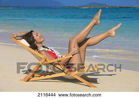 Picture - Hawaii, Oahu, Kailua, Lanikai, Beautiful woman stretches in a lounge chair on the beach.. Fotosearch