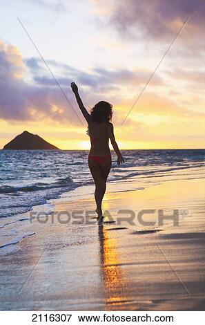 Stock Photo - Hawaii, Oahu, Kailua, Lanikai, Silhouette of a woman walking along the beach at sunrise.. Fotosearch