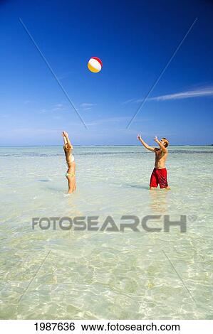 Stock Photograph - Hawaii, Oahu, Kaneohe, Couple Playing With Beach Ball In Crystal Clear Water At The Sandbar Or Dissapearing Island. Fotosearch