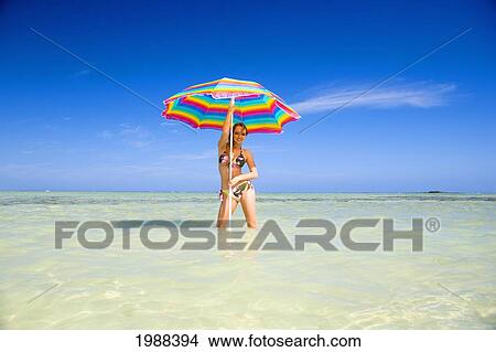 Picture - Hawaii, Oahu, Kaneohe, Woman Standing Under A Brightly Colored Umbrella In Crystal Clear Water At The Sandbar Or Dissapearing Island. Fotosearch