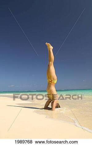 Stock Photo - Hawaii, Oahu, Lanikai, And Woman Stands On Her Head On The Beach.. Fotosearch