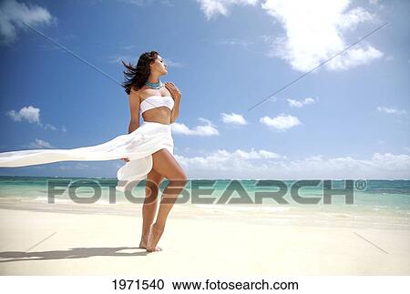 Stock Image - Hawaii, Oahu, Lanikai Beach, Beautiful Young Woman On Beach Wearing White Wrap.. Fotosearch
