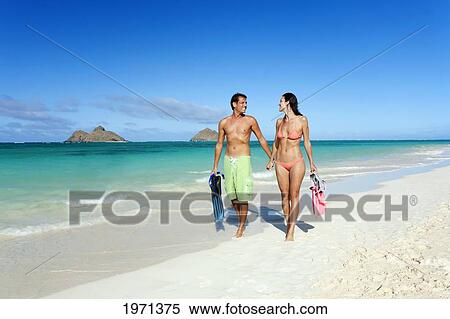 Stock Photography - Hawaii, Oahu, Lanikai Beach, Couple Walking Along Seashore With Snorkel Gear.. Fotosearch