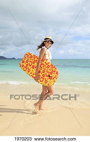 Stock Image - Hawaii, Oahu, Lanikai Beach, Girl Walking On The Beach With A Colorful Boogie Board.. Fotosearch