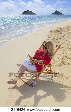 Picture - Hawaii, Oahu, Lanikai Beach, Woman reads book on white sandy beach.. Fotosearch