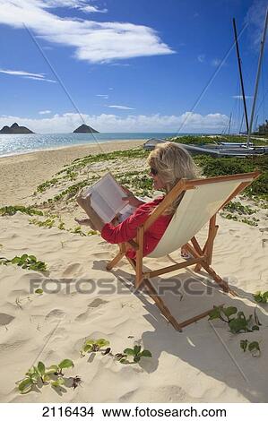 Picture - Hawaii, Oahu, Lanikai Beach, Woman reading a book on white sandy beach.. Fotosearch