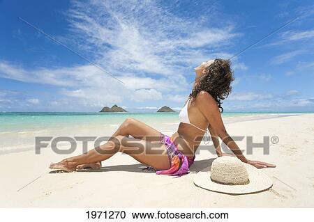 Stock Image - Hawaii, Oahu, Lanikai Beach, Woman Relaxing Along Sandy Shore.. Fotosearch