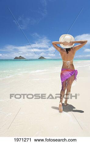 Stock Image - Hawaii, Oahu, Lanikai Beach, Woman Walking Along Sandy Shore.. Fotosearch