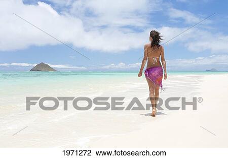 Stock Image - Hawaii, Oahu, Lanikai Beach, Woman Walking Along Sandy Shore.. Fotosearch