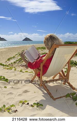 Stock Photo - Hawaii, Oahu, Lanikai Beach, Woman reading a book on white sandy beach.. Fotosearch