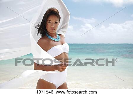 Stock Photograph - Hawaii, Oahu, Lanikai, Beautiful Young Woman Posing On Beach With White Fabric Blowing In The Wind.. Fotosearch