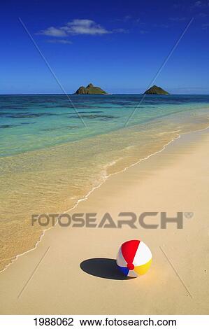 Stock Image - Hawaii, Oahu, Lanikai, Colorful Beachball On The Shore Of Tropical Beach, Mokulua Islands In Background.. Fotosearch