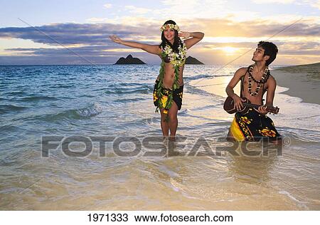 Stock Image - Hawaii, Oahu, Lanikai, Hula Dancer Couple Along Beach Shoreline At Sunrise.. Fotosearch
