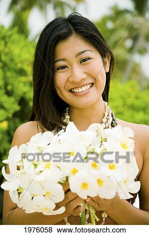 Stock Photo - Hawaii, Oahu, Lanikai, Japanese Woman Holding Plumeria Flowers.. Fotosearch