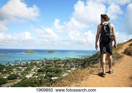 Stock Image - Hawaii, Oahu, Lanikai, Male Hiker Admiring View Of Mokulua Islands.. Fotosearch