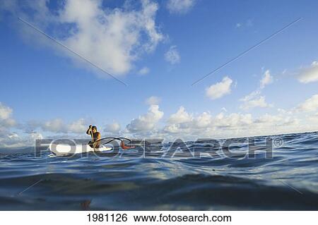 Stock Photograph - Hawaii, Oahu, Lanikai, Man Paddling One Man Outrigger Canoe, Land In Background.. Fotosearch