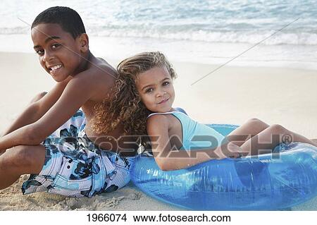Picture - Hawaii, Oahu, Lanikai, /Ntwo Children With Inflatable Toy Relax At Beach.. Fotosearch