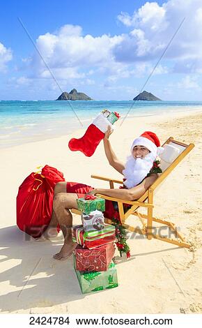Picture - Hawaii, Oahu, Lanikai, Polynesian male dressed as Santa Claus relaxes at the beach.. Fotosearch