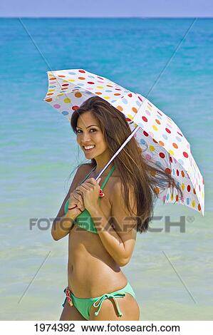 Stock Image - Hawaii, Oahu, Lanikai, Portrait Of Attractive Young Woman Holding An Umbrella.. Fotosearch