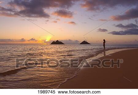 Stock Photography - Hawaii, Oahu, Lanikai, Sunrise, Silhouette Of Young Woman And Mokulua Islands In The Distance.. Fotosearch