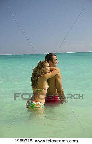 Stock Photography - Hawaii, Oahu, Lanikai, Woman Leaning On Man's Back In Turquoise Ocean.. Fotosearch