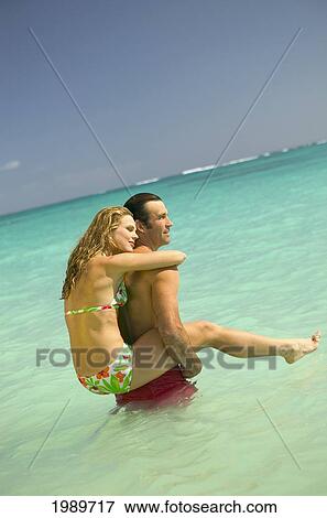 Stock Photo - Hawaii, Oahu, Lanikai, Woman On Man's Back In Turquoise Ocean.. Fotosearch