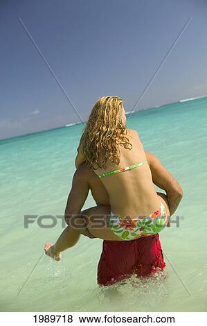 Stock Photo - Hawaii, Oahu, Lanikai, Woman On Man's Back In Turquoise Ocean.. Fotosearch
