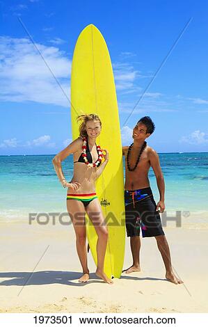 Stock Image - Hawaii, Oahu, Lanikai, Young Couple On The Beach With Their Surfboard.. Fotosearch
