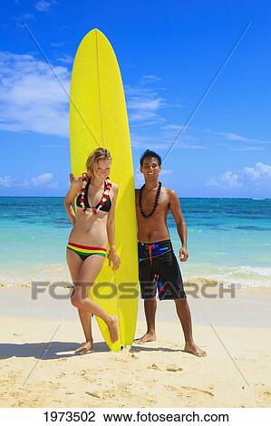 Stock Image - Hawaii, Oahu, Lanikai, Young Couple On The Beach With Their Surfboard.. Fotosearch