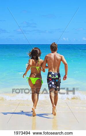 Picture - Hawaii, Oahu, Lanikai, Young Couple Running Into The Ocean.. Fotosearch